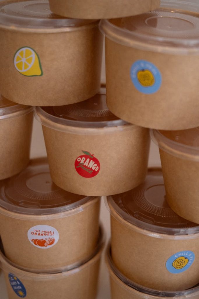 Eco-friendly paper food containers with various fruit labels stacked neatly.