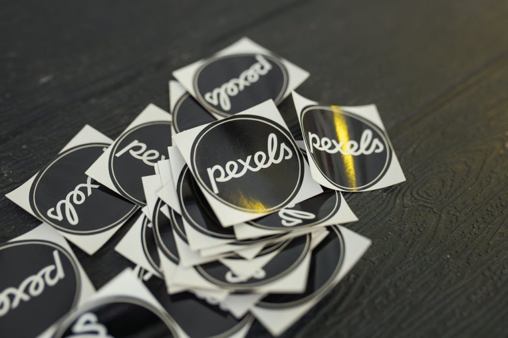 Round Labels A collection of Pexels branded stickers scattered on a dark wooden surface.
